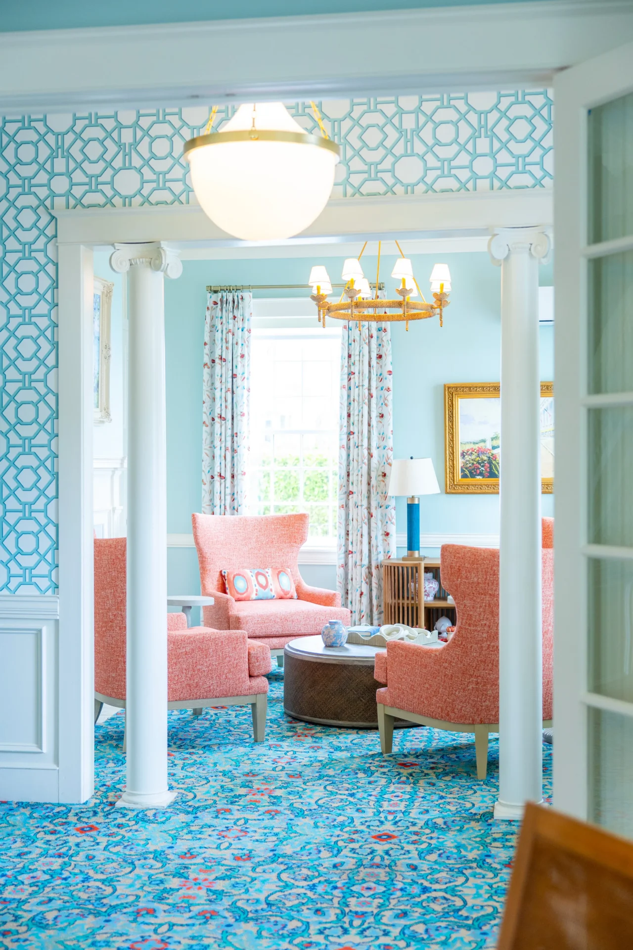 A blue room with pink chairs and chandelier.
