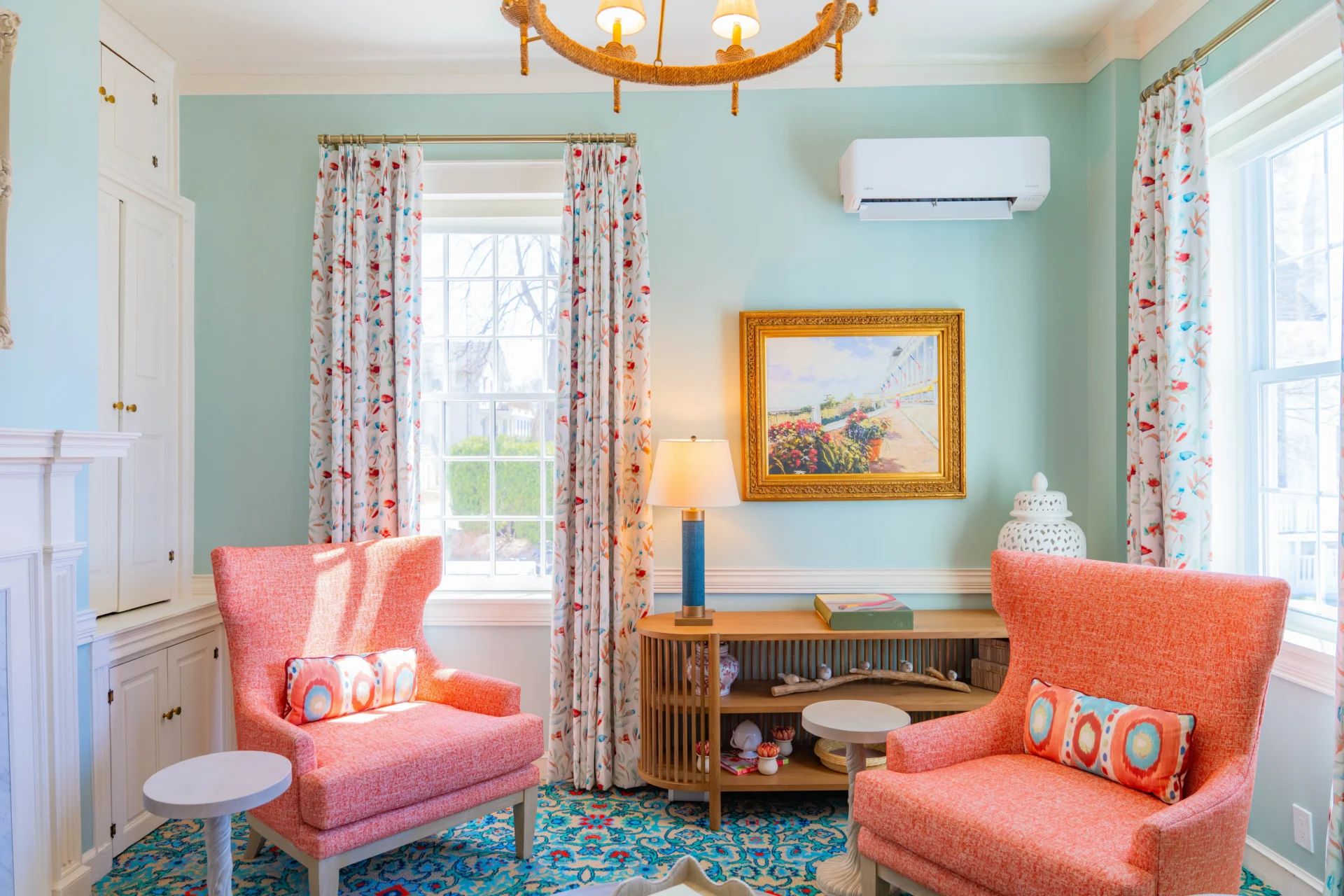 A green room with pattern carpet and pink chairs.