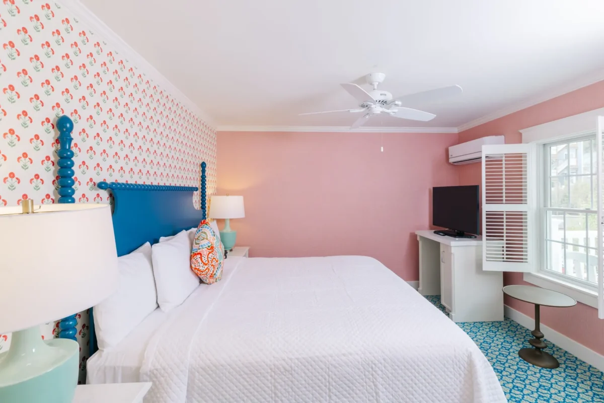 Pink room with polka dots with white bed with a window.