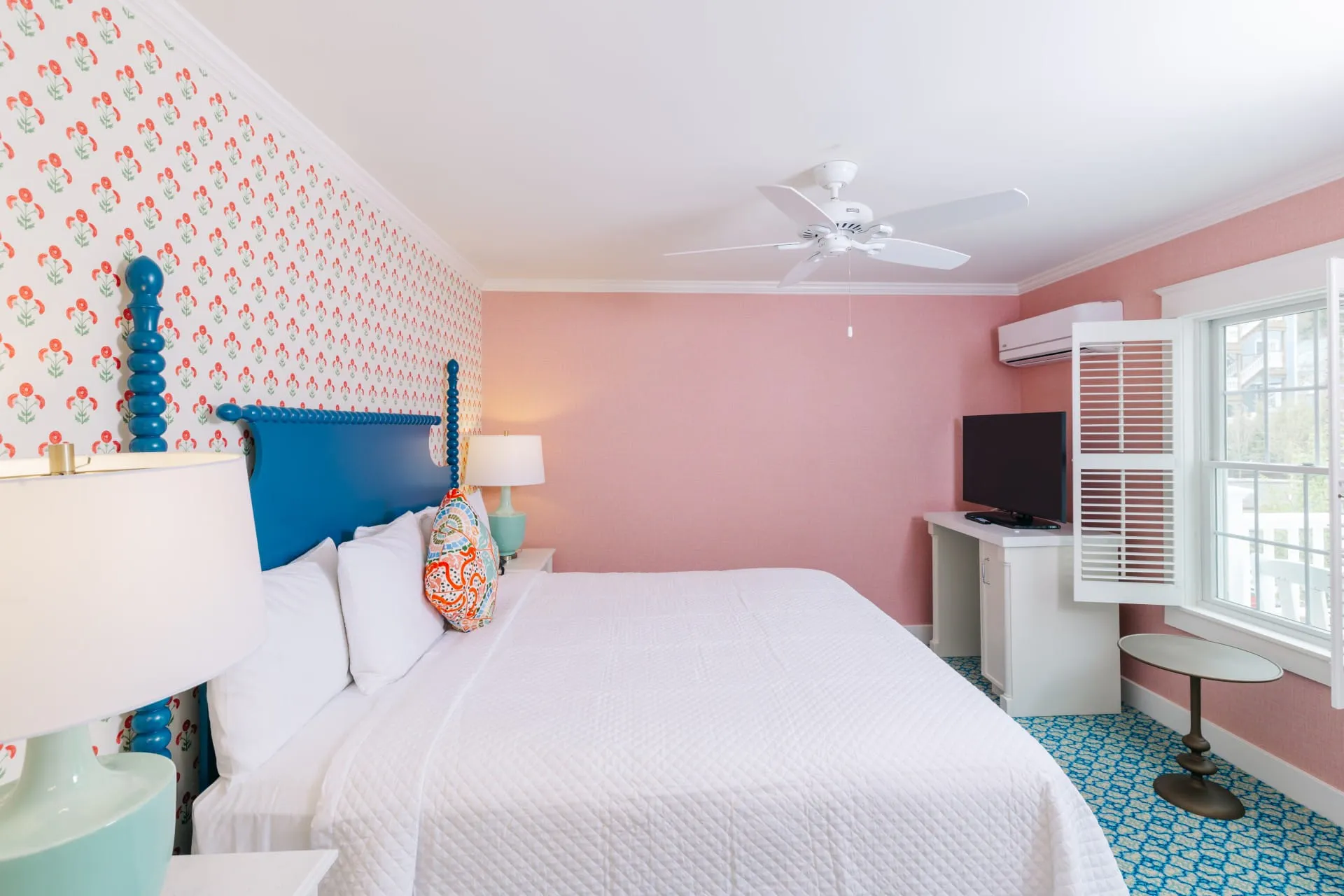 Pink room with polka dots with white bed with a window.